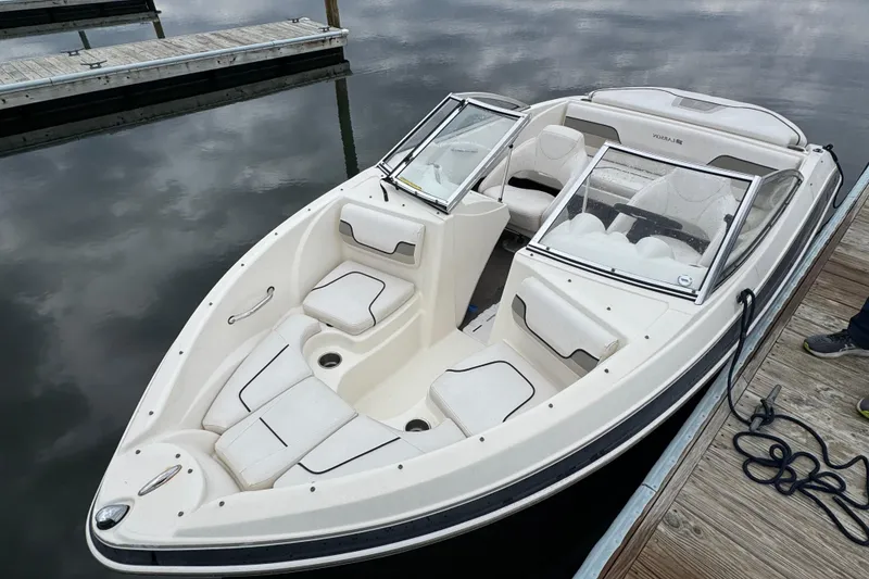 Slide: The Image of 2010 Larson LX 1750 boat docked, featuring sleek white interior and modern design. - 10