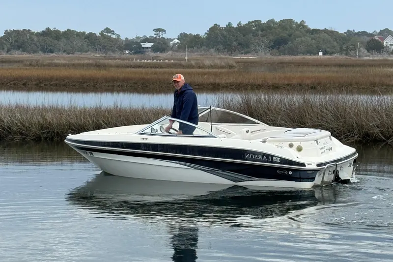 Slide: The Image of 2010 Larson LX 1750 boat on calm water with a person onboard, surrounded by marshland. - 3