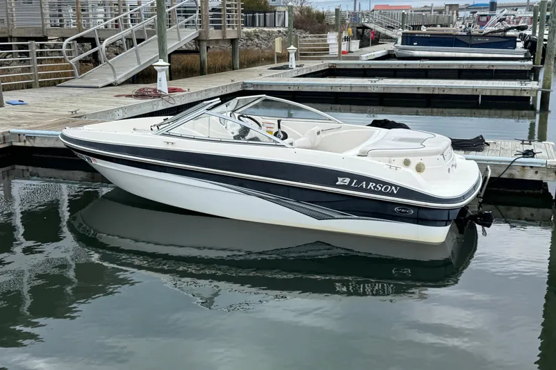 Slide: The Image of 2010 Larson LX 1750 boat docked at marina, sleek design, calm water reflection. - 5