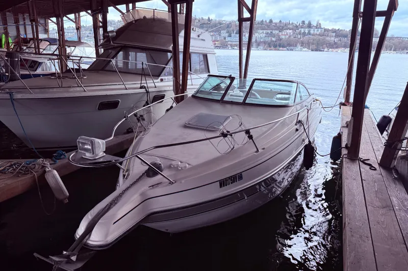 The Image of 2007 Glastron GS 279 boat docked in a marina, surrounded by calm waters. - 2