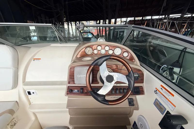 Slide: The Image of 2007 Glastron GS 279 boat dashboard with steering wheel and gauges in a marina setting. - 9