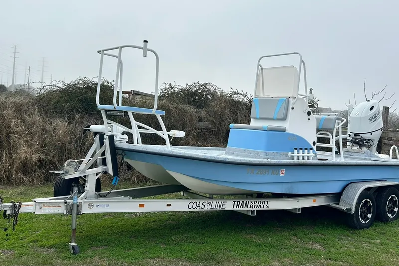 Slide: The Image of 2022 Transcat 200 SVT boat on trailer, featuring blue and white design, parked on grass. - 2