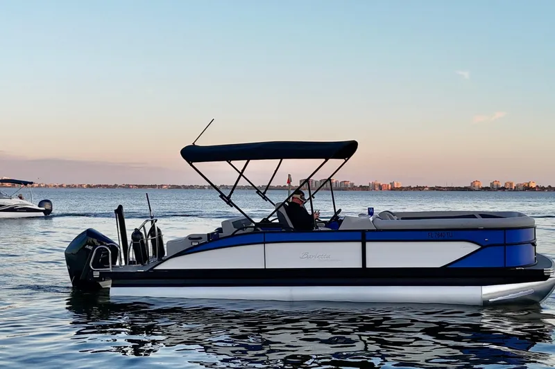 Slide: The Image of 2024 Barletta Cabrio 24UC pontoon boat on calm water at sunset. - 13