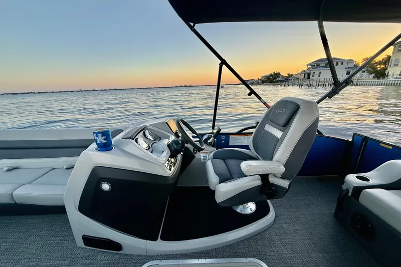Slide: The Image of 2024 Barletta Cabrio 24UC boat interior with captain's chair, sunset view over water. - 22