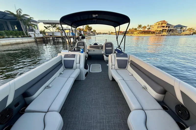 Slide: The Image of 2024 Barletta Cabrio 24UC pontoon boat interior with spacious seating on a serene waterway. - 27