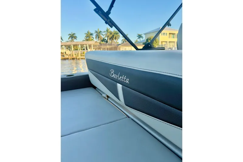 Slide: The Image of 2024 Barletta Cabrio 24UC boat interior with elegant seating and scenic waterfront view. - 28