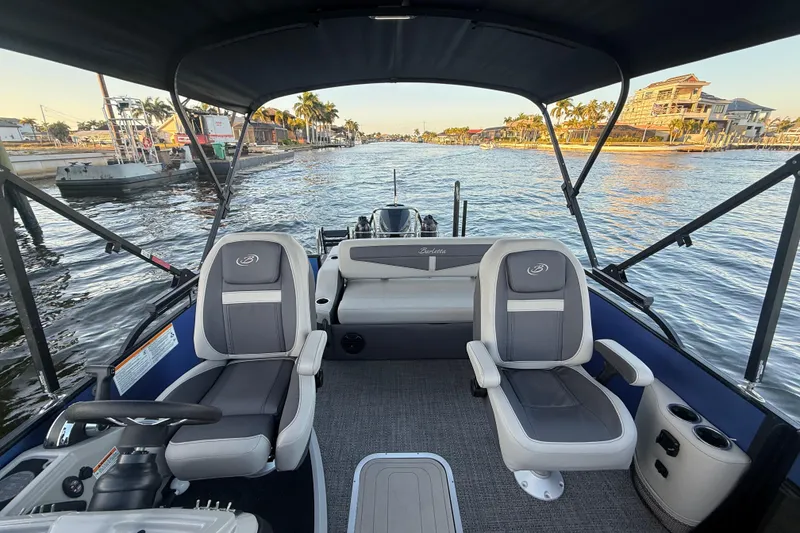 Slide: The Image of 2024 Barletta Cabrio 24UC pontoon boat interior with plush seating on a scenic waterway. - 29
