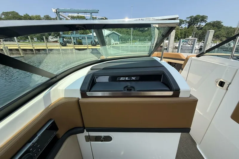 Slide: The Image of 2016 Sea Ray SLX 250 boat interior with brown and white seating, dockside view. - 15