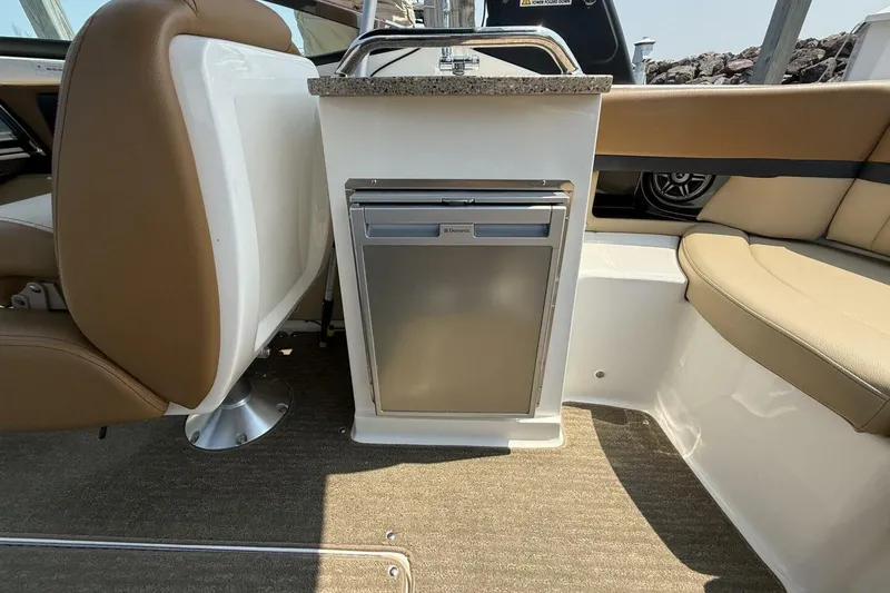 Slide: The Image of 2016 Sea Ray SLX 250 boat interior with seating and built-in mini fridge. - 28
