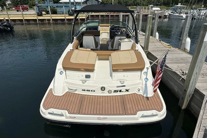 Slide: The Image of 2016 Sea Ray SLX 250 boat docked, featuring tan seating and American flag. - 3