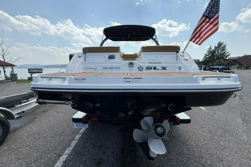 Slide: The Image of 2016 Sea Ray SLX 250 boat with American flag, parked near a lake. - 43