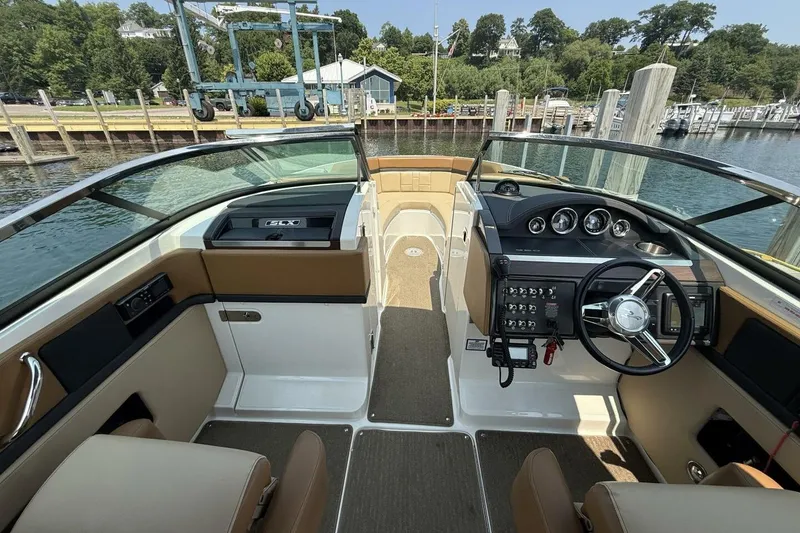 Slide: The Image of 2016 Sea Ray SLX 250 boat interior with steering wheel, dashboard, and seating at a marina. - 6