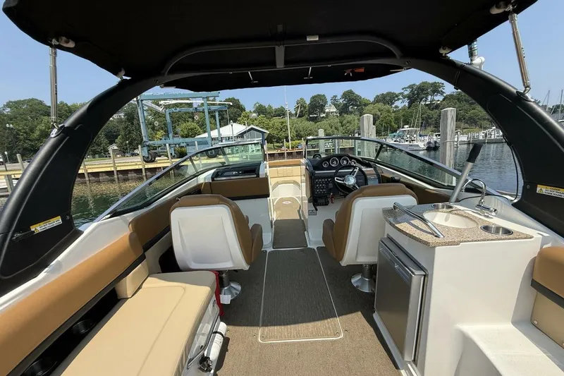 Slide: The Image of 2016 Sea Ray SLX 250 boat interior with seating, helm, and kitchenette at a marina. - 7