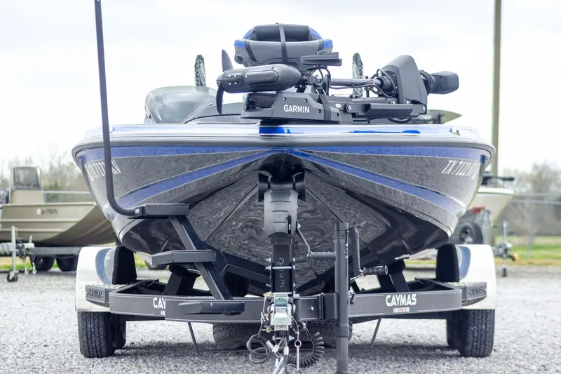 Slide: The Image of 2023 Caymas CX 21 PRO boat on trailer, featuring Garmin equipment, parked outdoors. - 2