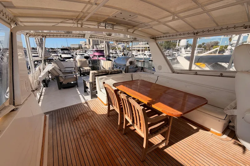 Slide: The Image of 1984 Hartman-Palmer 60 Flush Deck Motor Yacht interior with wooden table and marina view. - 55