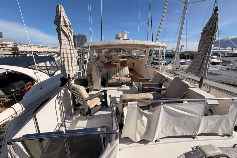 Slide: The Image of 1984 Hartman-Palmer 60 Flush Deck Motor Yacht with outdoor seating and umbrellas at marina. - 59