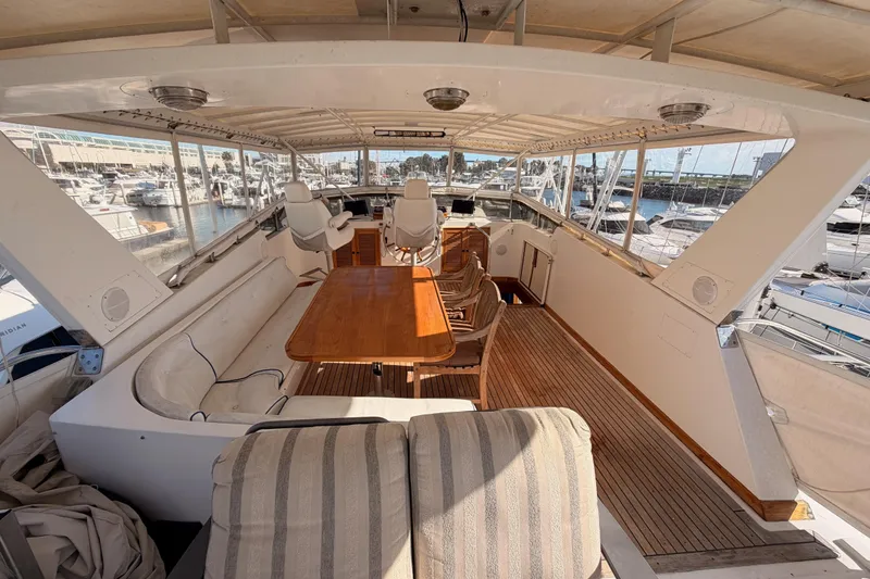 Slide: The Image of 1984 Hartman-Palmer 60 Flush Deck Motor Yacht interior with seating and table, docked at marina. - 62