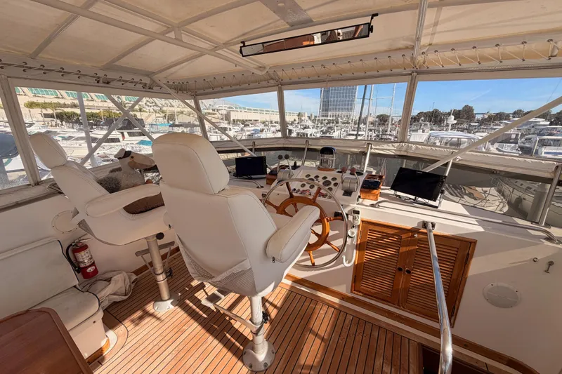Slide: The Image of 1984 Hartman-Palmer 60 Flush Deck Motor Yacht helm with dual captain chairs and panoramic marina view. - 63