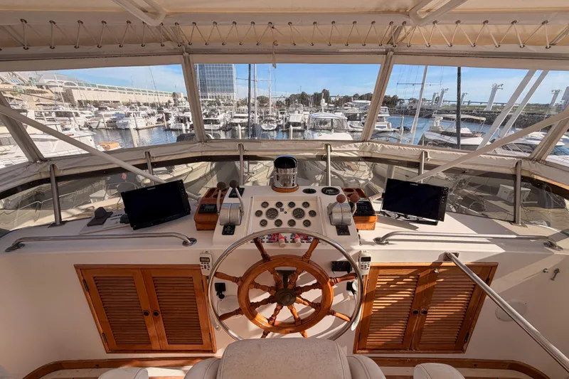 Slide: The Image of 1984 Hartman-Palmer 60 Flush Deck Motor Yacht helm with marina view, featuring navigation equipment. - 64