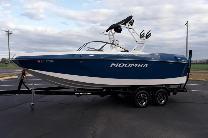 Slide: The Image of 2024 Moomba Max boat on trailer, blue and white design, parked outdoors. - 16
