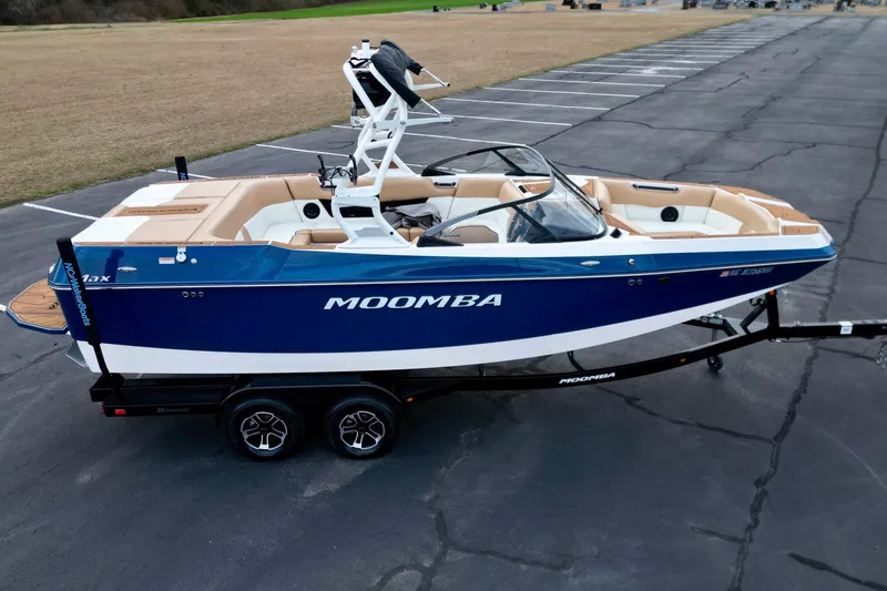 Slide: The Image of 2024 Moomba Max boat on trailer, blue and white design, parked on asphalt. - 25