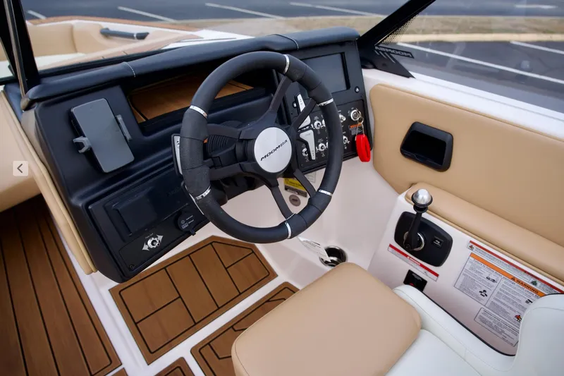 Slide: The Image of 2024 Moomba Max boat interior with steering wheel and control panel, featuring tan and black accents. - 9