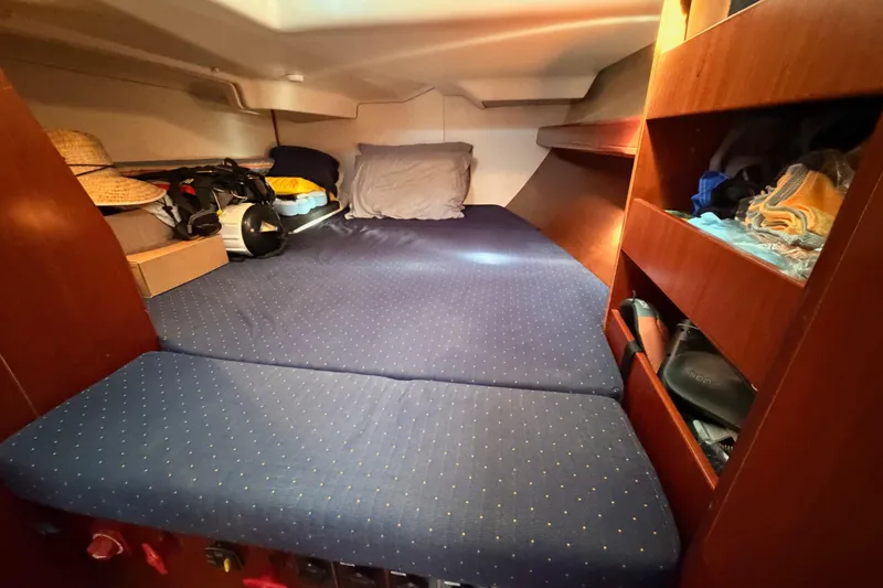 Slide: The Image of Cozy cabin interior of 2005 Beneteau Oceanis Clipper 423 with blue bedding and wooden shelves. - 50
