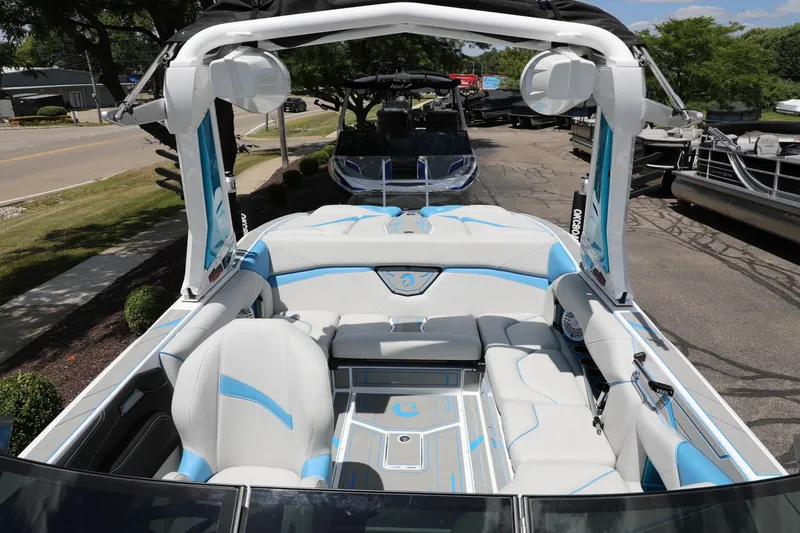Slide: The Image of 2026 Centurion Nv233 boat interior with white and blue seating, parked outdoors. - 2