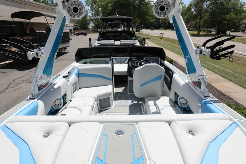Slide: The Image of 2026 Centurion Nv233 boat interior with white and blue seating, speakers, and modern dashboard. - 7