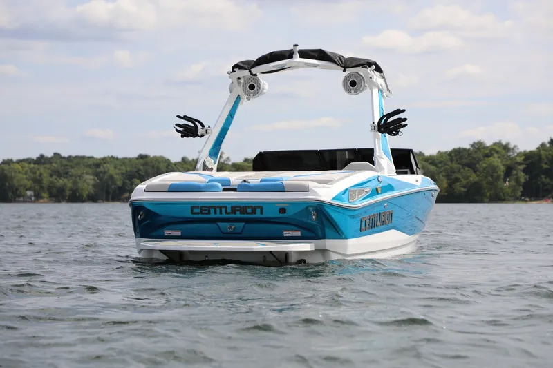 Slide: The Image of 2026 Centurion Nv233 boat on a lake, showcasing sleek design and vibrant blue color. - 1