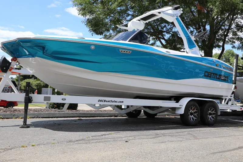 Slide: The Image of 2026 Centurion Nv233 boat on trailer, vibrant blue and white design, parked outdoors. - 6