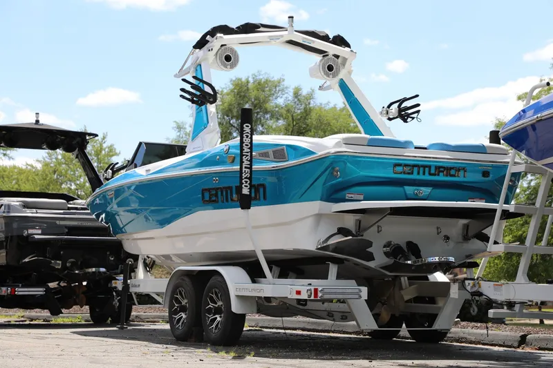Slide: The Image of 2026 Centurion Nv233 boat on trailer, vibrant blue and white design. - 13