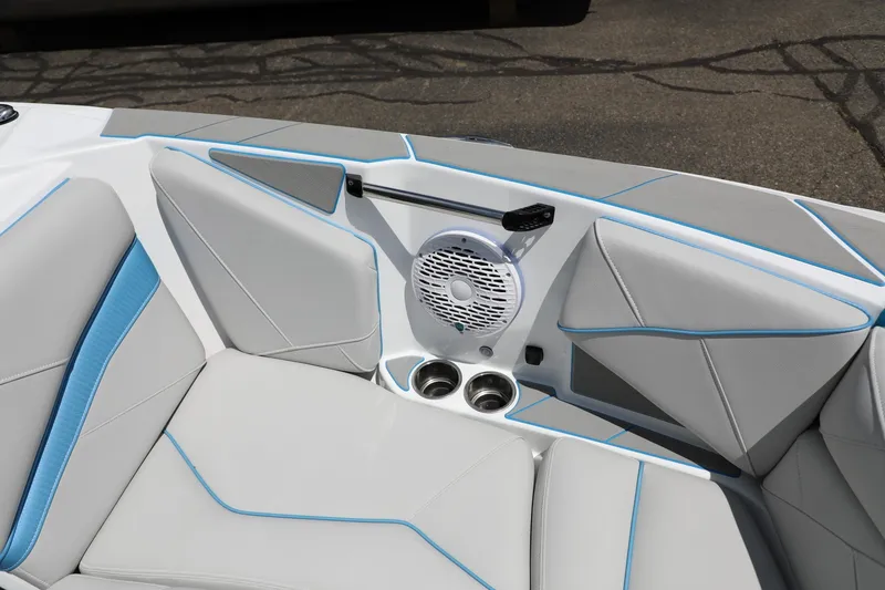 Slide: The Image of 2026 Centurion Nv233 boat interior with gray and blue seating, speaker, and cup holders. - 12