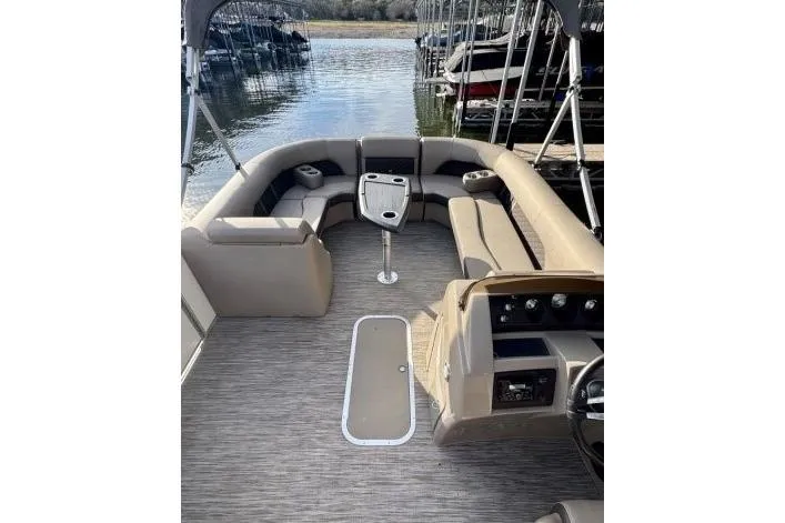 Slide: The Image of 2021 Bennington L 24 Swingback pontoon boat interior with seating and table, docked by the water. - 12