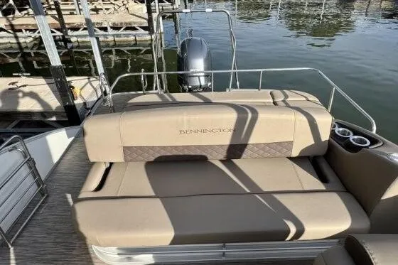 Slide: The Image of 2021 Bennington L 24 Swingback boat with beige seating and cup holders by the water. - 14