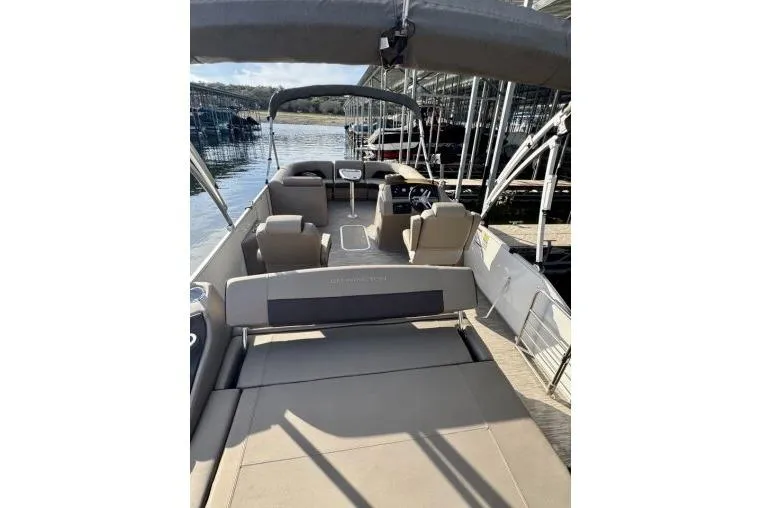 Slide: The Image of 2021 Bennington L 24 Swingback pontoon boat docked, featuring spacious seating and canopy. - 16
