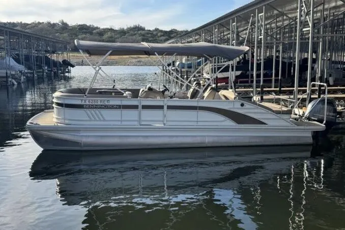Slide: The Image of 2021 Bennington L 24 Swingback pontoon boat docked in a marina, featuring a canopy. - 29