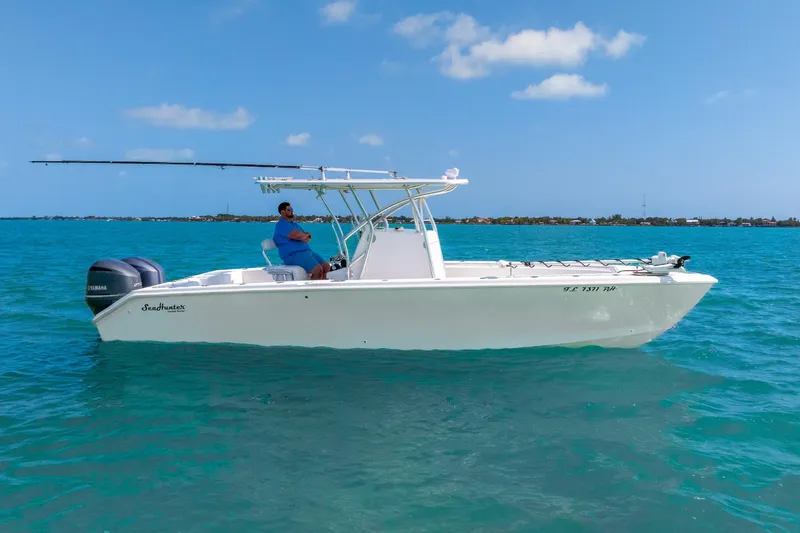 Slide: The Image of 2012 SeaHunter 29 boat on clear blue water with a person at the helm. - 13