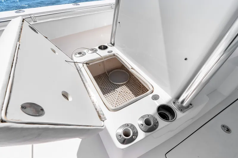 Slide: The Image of Open storage compartment on 2012 SeaHunter 29 boat, featuring rod holders and ocean backdrop. - 34