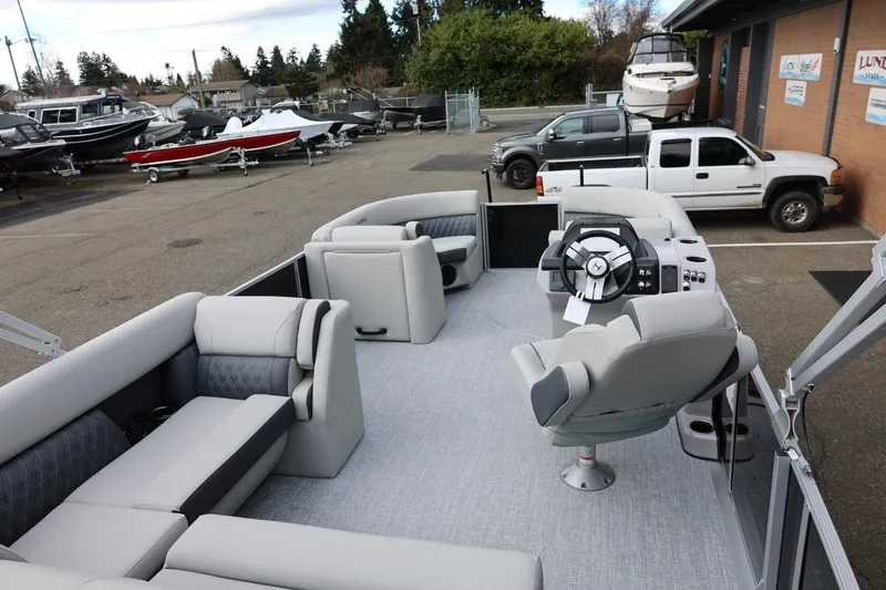Slide: The Image of 2026 Harris Cruiser 210 SL pontoon boat with modern seating and steering, parked in a marina. - 19