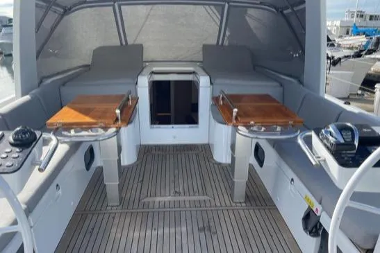 Slide: The Image of 2022 Beneteau Oceanis Yacht 54 cockpit with wooden tables and cushioned seating. - 23