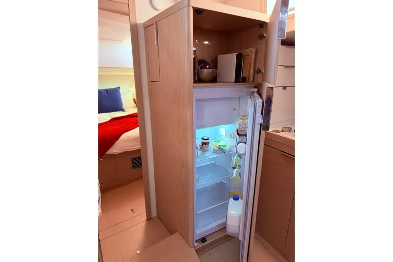 Slide: The Image of Open fridge in 2022 Beneteau Oceanis Yacht 54, showcasing interior storage and adjacent cabin. - 37