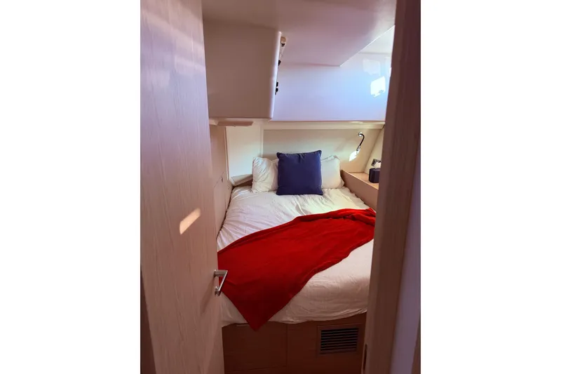 Slide: The Image of Cozy cabin interior of 2022 Beneteau Oceanis Yacht 54 with red blanket and pillows. - 38