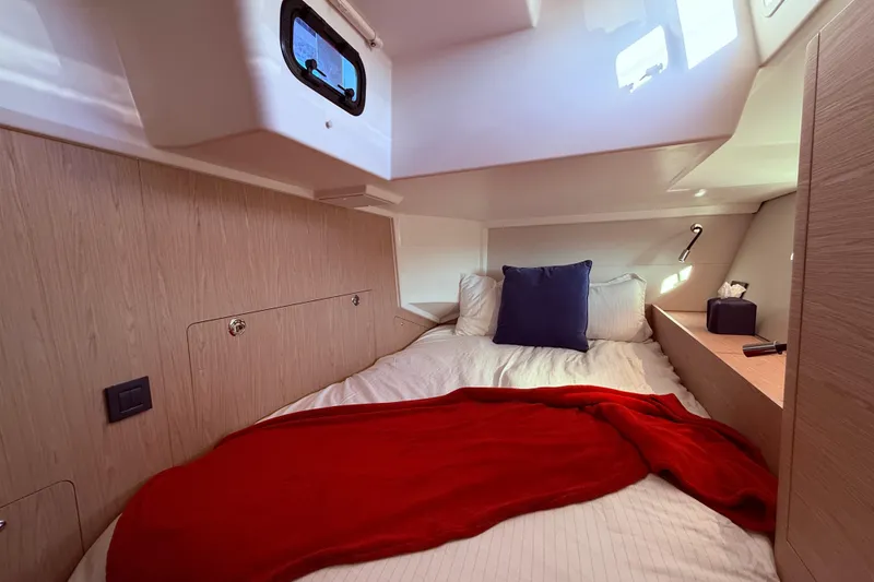Slide: The Image of Cozy cabin interior of 2022 Beneteau Oceanis Yacht 54 with red blanket and blue pillow. - 39
