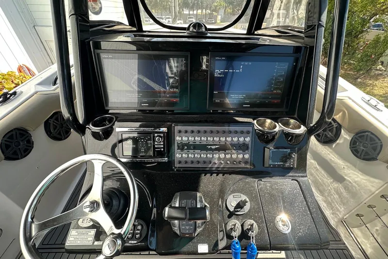 Slide: The Image of 2018 Tidewater 320 CC Adventure boat dashboard with dual screens and steering wheel. - 12