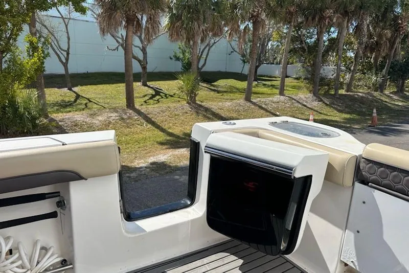 Slide: The Image of 2018 Tidewater 320 CC Adventure boat interior with seating and storage, surrounded by trees. - 13