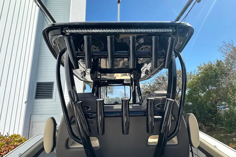 Slide: The Image of 2018 Tidewater 320 CC Adventure boat with rod holders and T-top, viewed from the rear. - 16