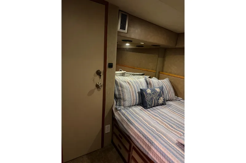 Slide: The Image of Cozy bedroom interior of 1984 Bertram 42 Convertible yacht with striped bedding and floral pillow. - 20