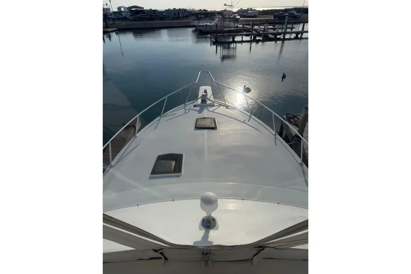 Slide: The Image of 1984 Bertram 42 Convertible yacht bow view at marina, reflecting sunlight on water. - 3