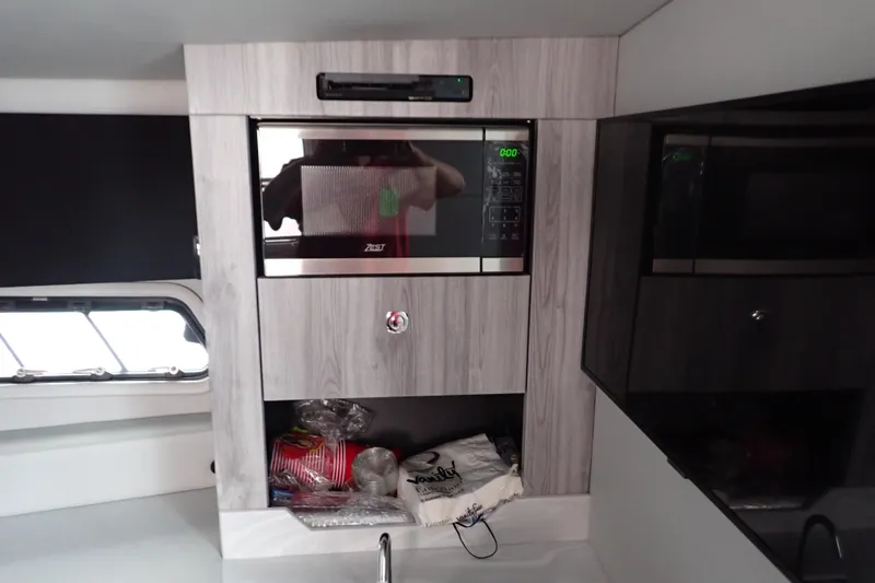 Slide: The Image of 2023 Formula 380 Super Sport Crossover OB interior kitchen with microwave and storage. - 46